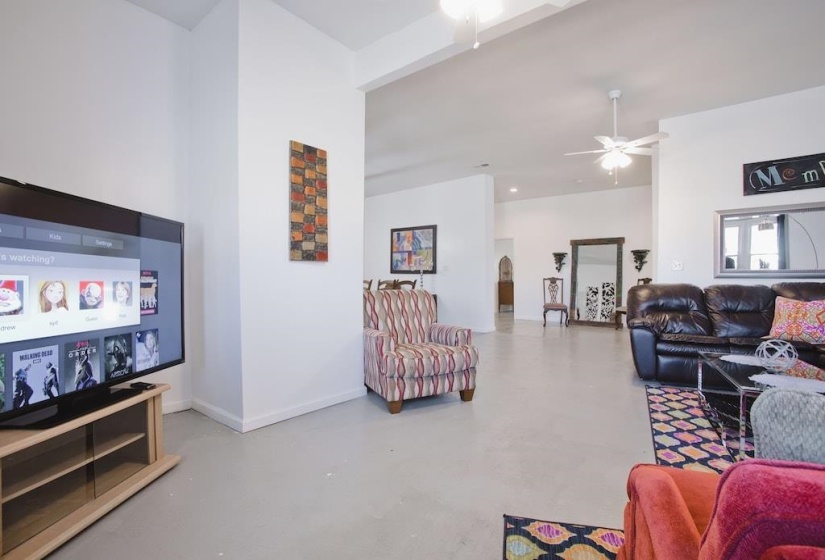 Living area featuring finished concrete floors and ceiling fan