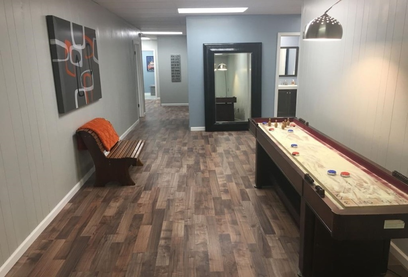 Recreation room with wood walls and dark wood-type flooring