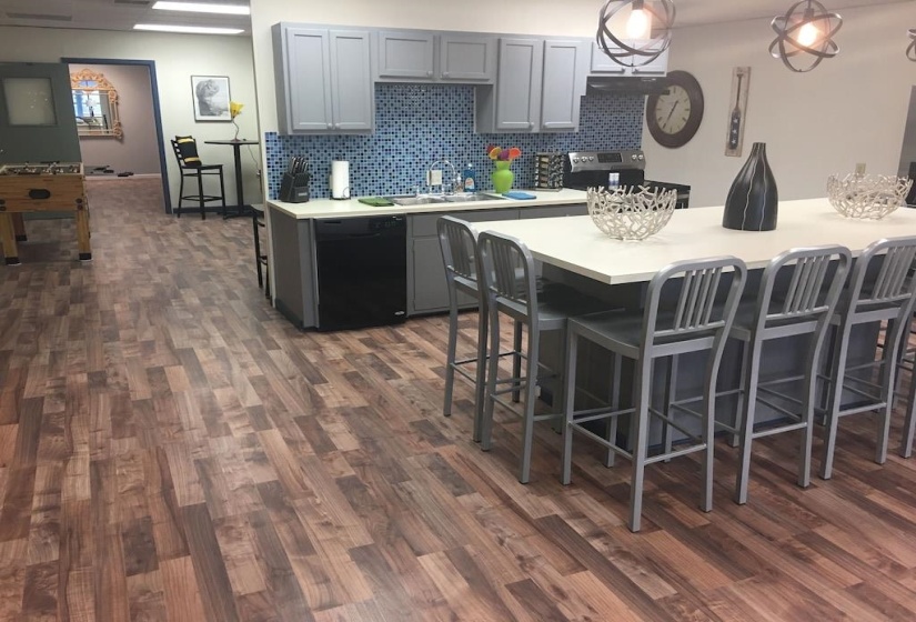 Kitchen featuring gray cabinets, black dishwasher, a breakfast bar area, and dark wood-type flooring