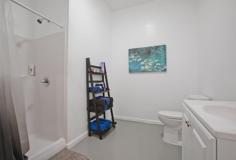 Full bath featuring a shower stall, vanity, and finished concrete flooring