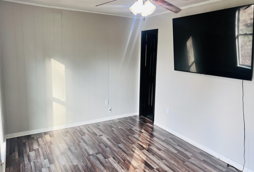 Unfurnished room with wood finished floors, crown molding, a ceiling fan, and wood walls