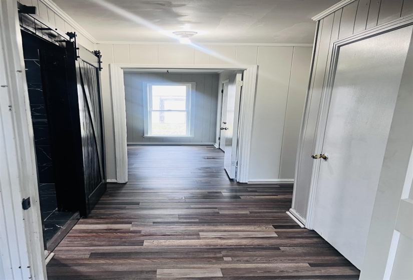 Hallway with a barn door, dark wood-style flooring, and ornamental molding