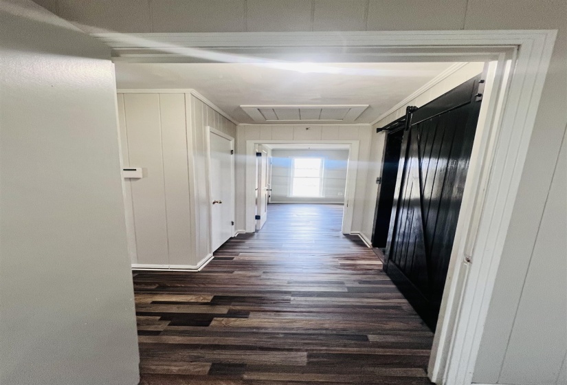 Hall featuring dark wood-type flooring, a barn door, and attic access