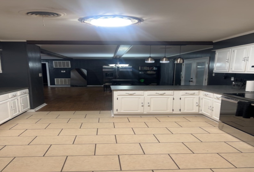 Kitchen featuring white cabinets, a peninsula, stainless steel range with electric stovetop, hanging light fixtures, and beam ceiling