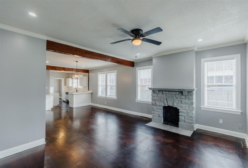 Unfurnished living room with a fireplace, plenty of natural light, dark wood-type flooring, and a textured ceiling