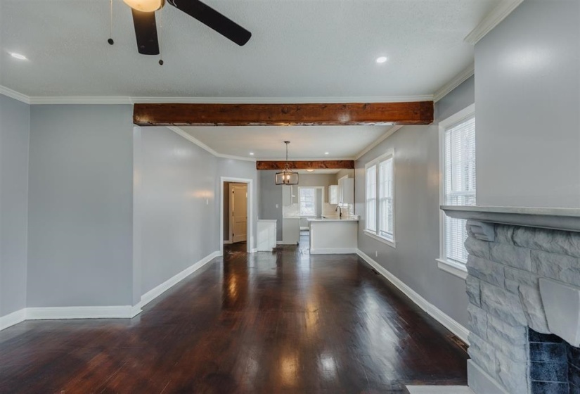 Unfurnished living room featuring ceiling fan, ornamental molding, a fireplace, and dark wood-type flooring