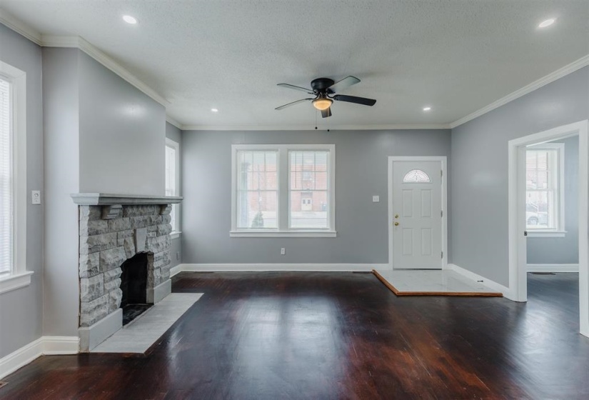Foyer entrance featuring ceiling fan, crown molding, a fireplace, dark hardwood / wood-style floors, and a textured ceiling