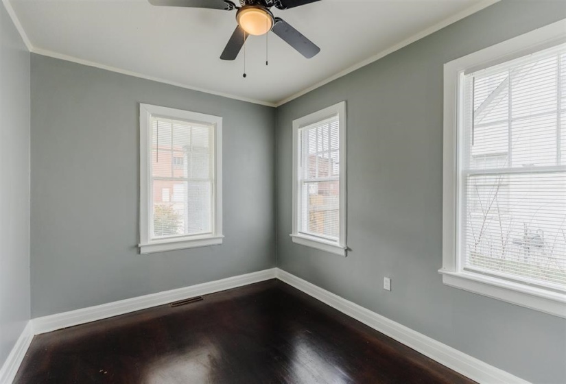 Empty room featuring ornamental molding, hardwood / wood-style flooring, and ceiling fan