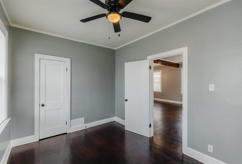Empty room with dark hardwood / wood-style floors, ornamental molding, and ceiling fan