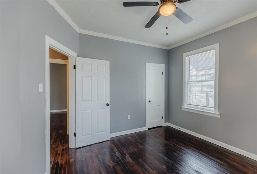 Unfurnished bedroom featuring ceiling fan, a textured ceiling, crown molding, and dark hardwood / wood-style flooring