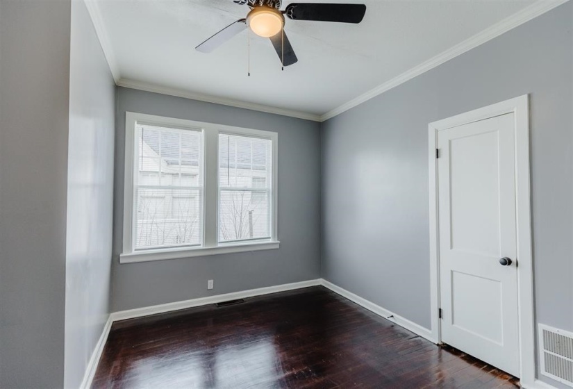Empty room featuring ceiling fan, crown molding, and dark hardwood / wood-style flooring