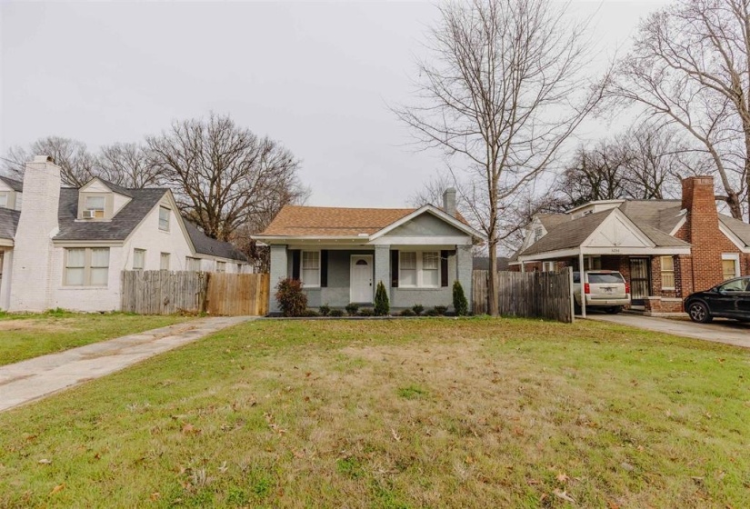 View of front of home with a front yard, covered porch, and a carport