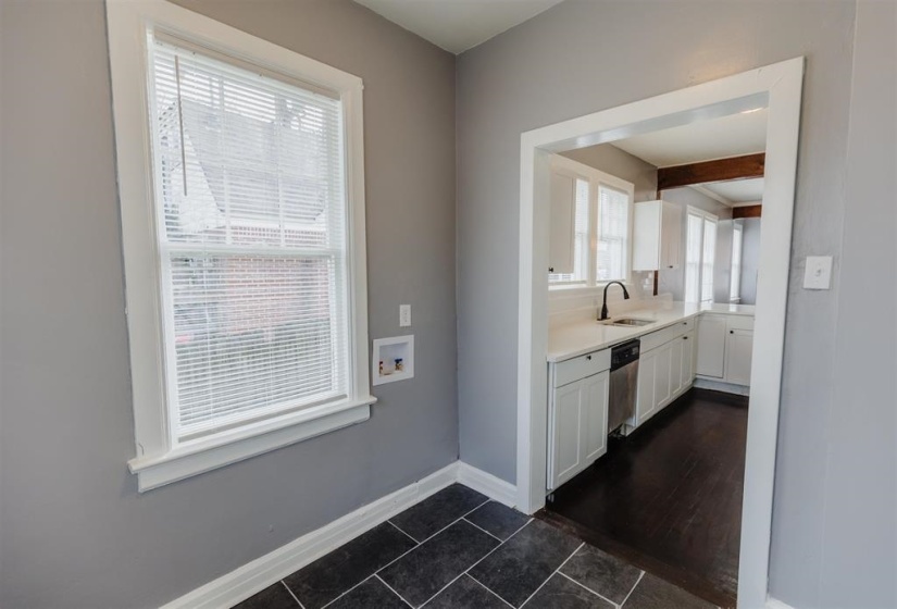 Kitchen with beamed ceiling, dark wood-type flooring, sink, stainless steel dishwasher, and white cabinetry