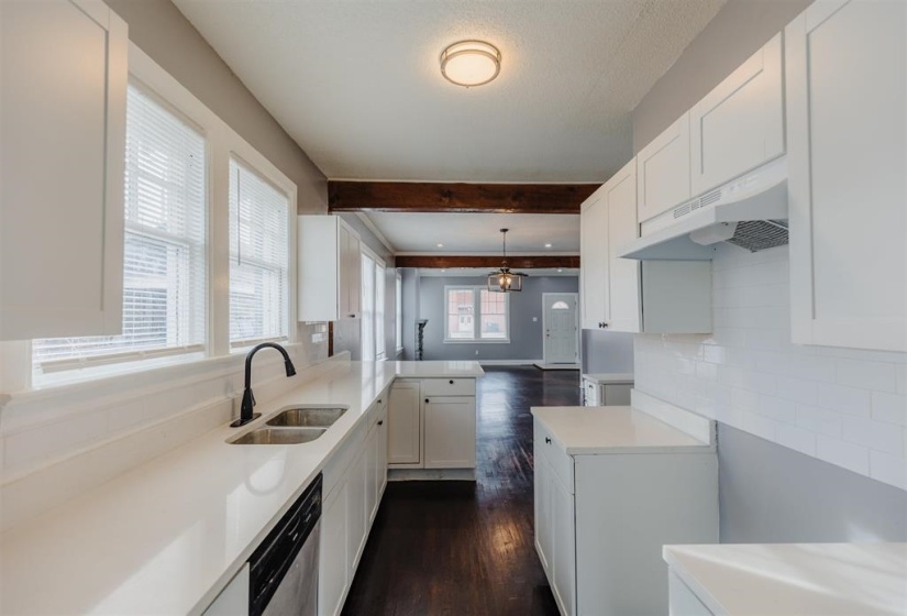 Kitchen with a healthy amount of sunlight, pendant lighting, dark wood-type flooring, exhaust hood, and white cabinetry