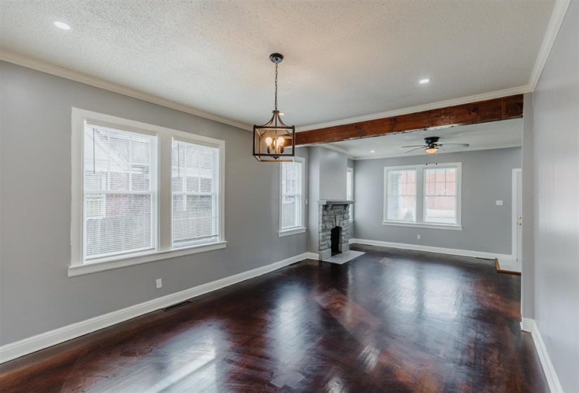 Unfurnished dining area with a textured ceiling, a fireplace, ceiling fan with notable chandelier, crown molding, and dark hardwood / wood-style flooring