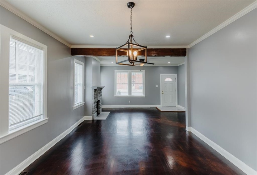 Interior space featuring ornamental molding, a chandelier, dark hardwood / wood-style flooring, and a stone fireplace