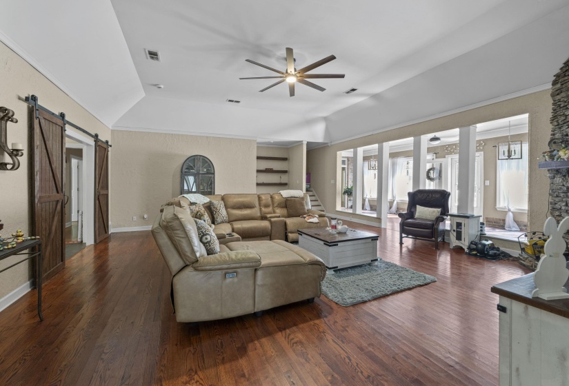 Living room with visible vents, a wealth of natural light, ceiling fan, and a barn door