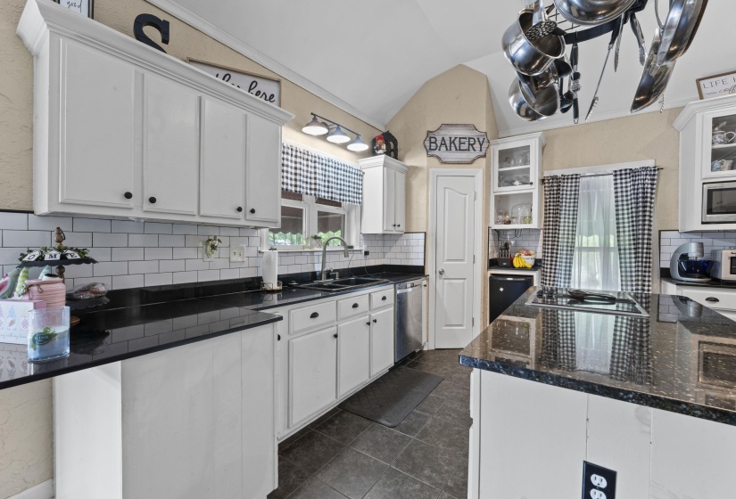 Kitchen with white cabinets, vaulted ceiling, stainless steel appliances, and a sink