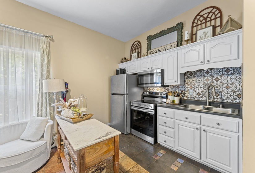 Kitchen featuring a sink, dark countertops, white cabinetry, decorative backsplash, and appliances with stainless steel finishes