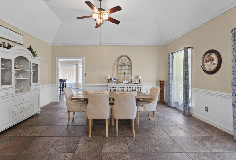 Dining area with vaulted ceiling, ceiling fan, and wainscoting