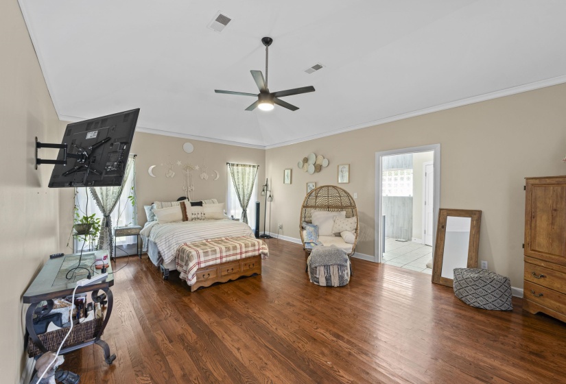 Bedroom featuring visible vents, baseboards, wood finished floors, and crown molding
