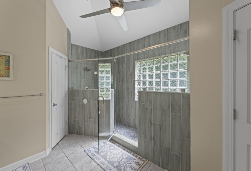 Bathroom featuring a tile shower, lofted ceiling, tile patterned flooring, and ceiling fan