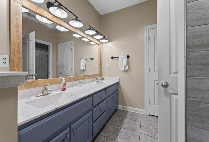 Full bathroom with tile patterned floors, baseboards, a sink, and double vanity