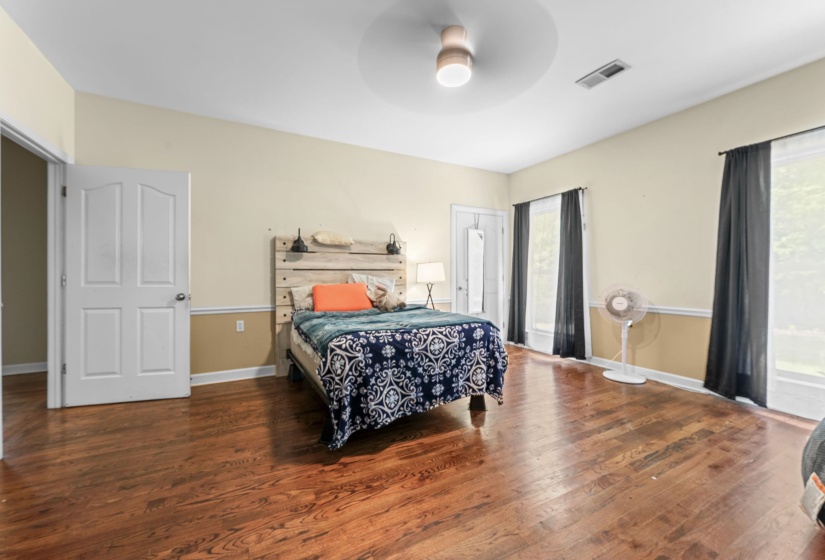 Bedroom with wood finished floors and multiple windows