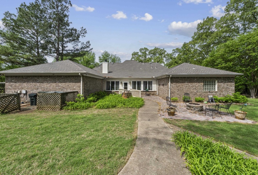 Back of house featuring a chimney, a yard, a patio area, an outdoor fire pit, and brick siding