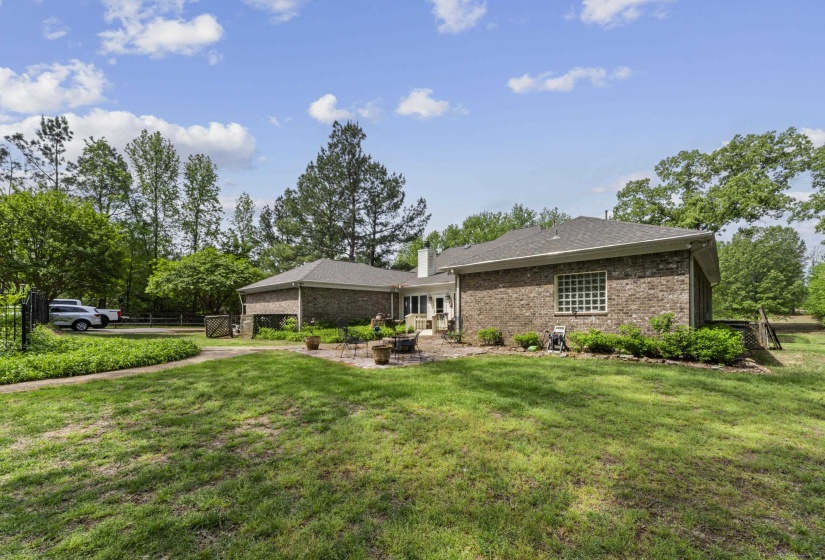 Exterior space featuring a chimney, brick siding, a front yard, and a patio