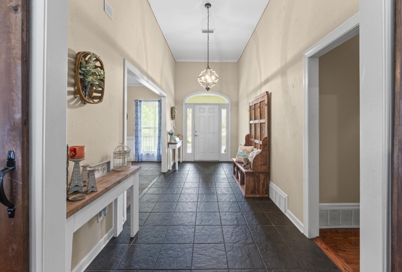 Foyer entrance featuring stone tile flooring, baseboards, and visible vents