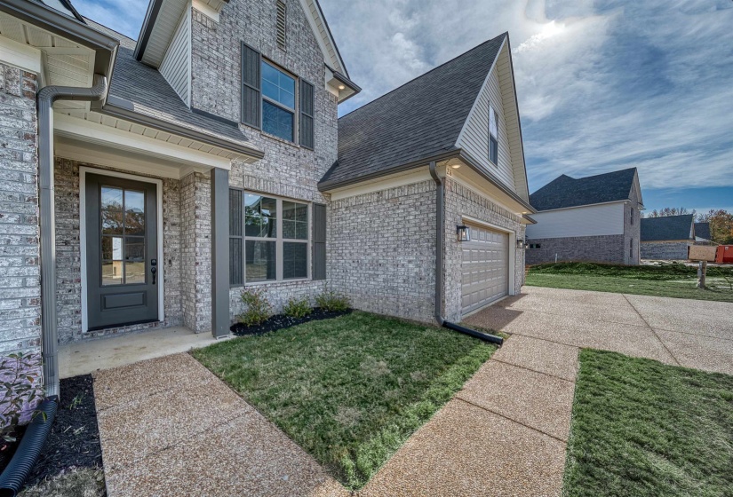 Property entrance with a garage, a yard, a shingled roof, and brick siding