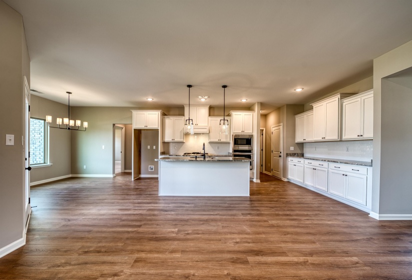 Kitchen with tasteful backsplash, a chandelier, white cabinetry, decorative light fixtures, and dark wood finished floors