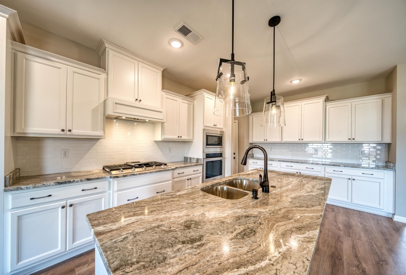 Kitchen with backsplash, white cabinets, light stone countertops, dark wood-type flooring, and recessed lighting