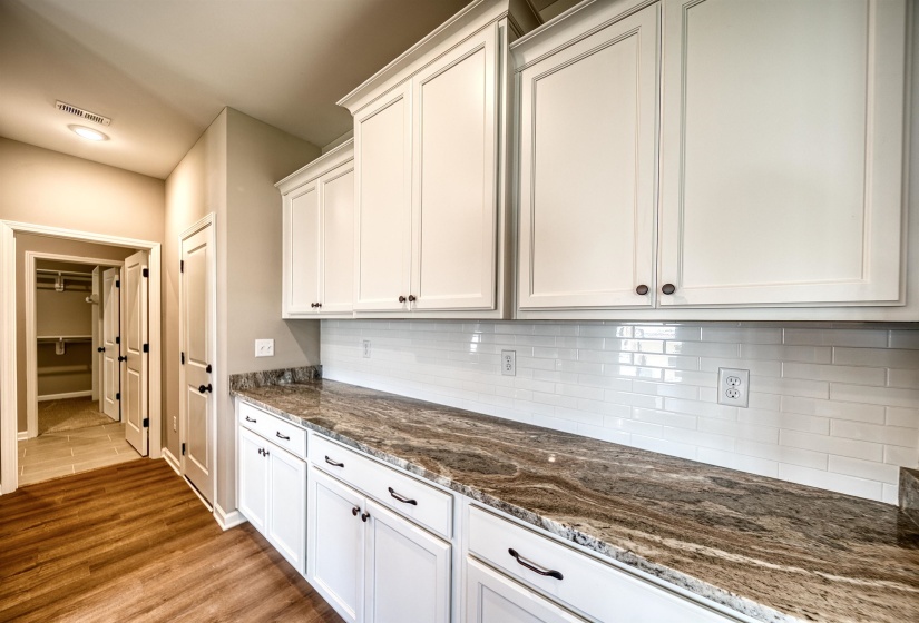 Kitchen featuring dark stone countertops, decorative backsplash, white cabinetry, and light wood-type flooring