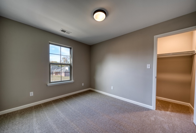 Unfurnished bedroom with a walk in closet and light carpet