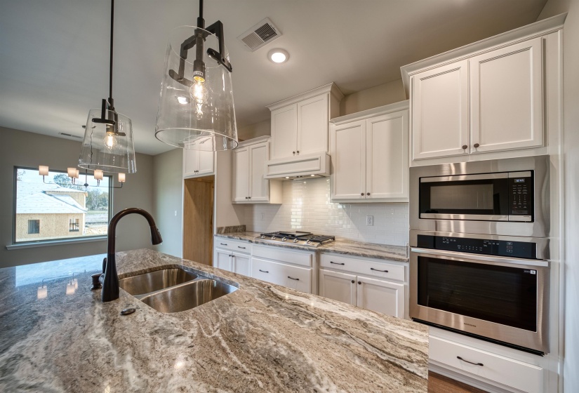 Kitchen featuring tasteful backsplash, stainless steel appliances, light stone countertops, and recessed lighting