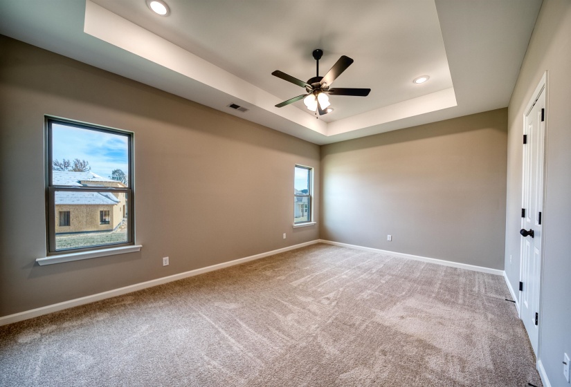 Spare room with a raised ceiling, light carpet, ceiling fan, and recessed lighting