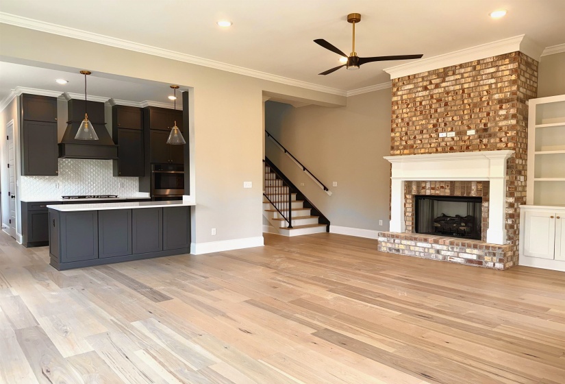 Unfurnished living room featuring ornamental molding, light wood-type flooring, ceiling fan, recessed lighting, and a fireplace