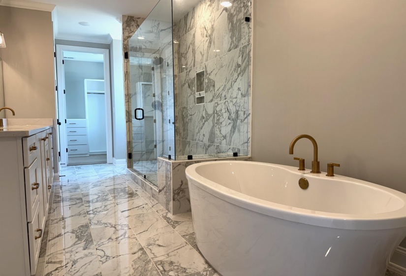 Full bath with vanity, a marble finish shower, a freestanding bath, and light marble finish flooring