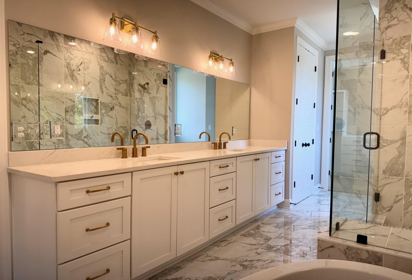 Full bath with light marble finish flooring, a marble finish shower, ornamental molding, double vanity, and a freestanding tub