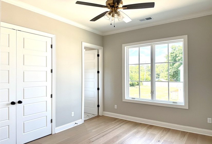 Unfurnished bedroom with ornamental molding, light wood-type flooring, a closet, and a ceiling fan