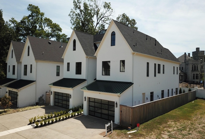 View of front facade featuring an attached garage, driveway, a standing seam roof, a metal roof, and stucco siding