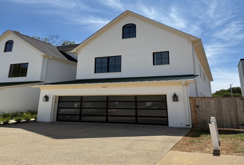 View of side of property with brick siding, an attached garage, driveway, and a metal roof