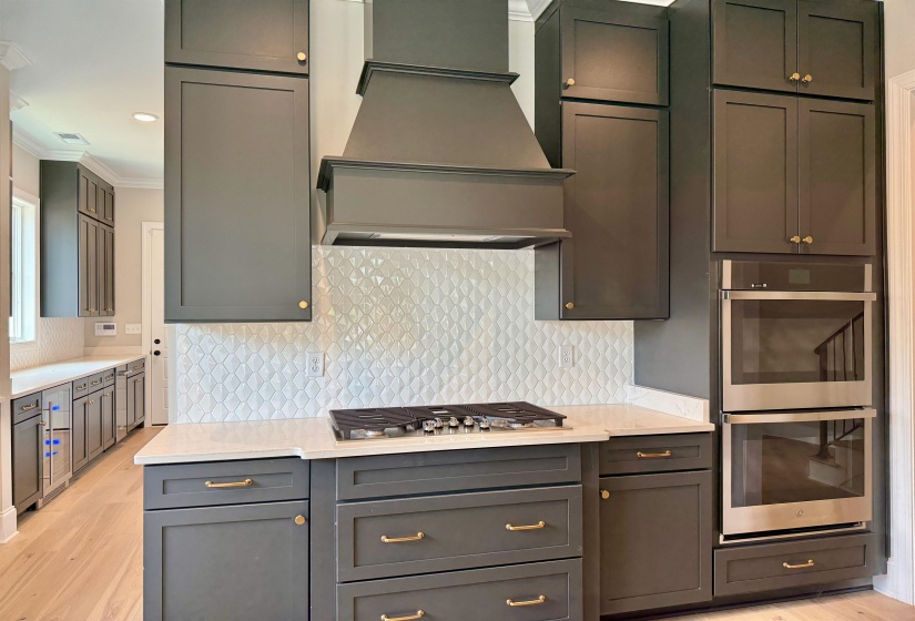 Kitchen with tasteful backsplash, appliances with stainless steel finishes, custom exhaust hood, light wood finished floors, and recessed lighting