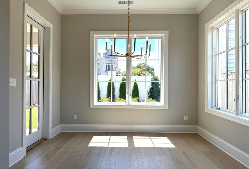 Unfurnished dining area with ornamental molding, plenty of natural light, a chandelier, and wood finished floors
