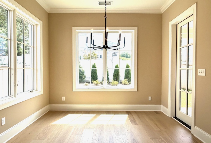 Unfurnished dining area featuring light wood-type flooring, a chandelier, crown molding, and plenty of natural light