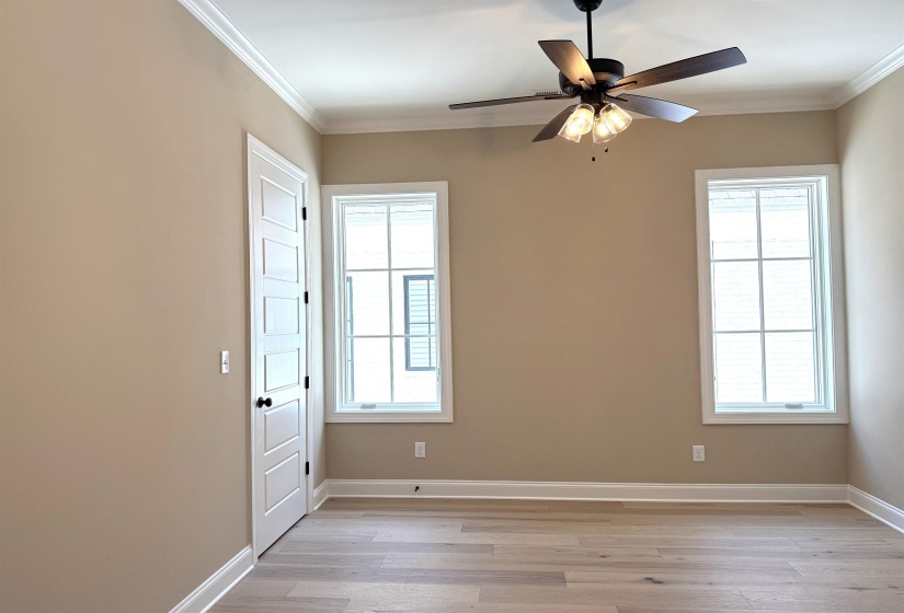 Bedroom with ornamental molding, light wood-type flooring, and ceiling fan