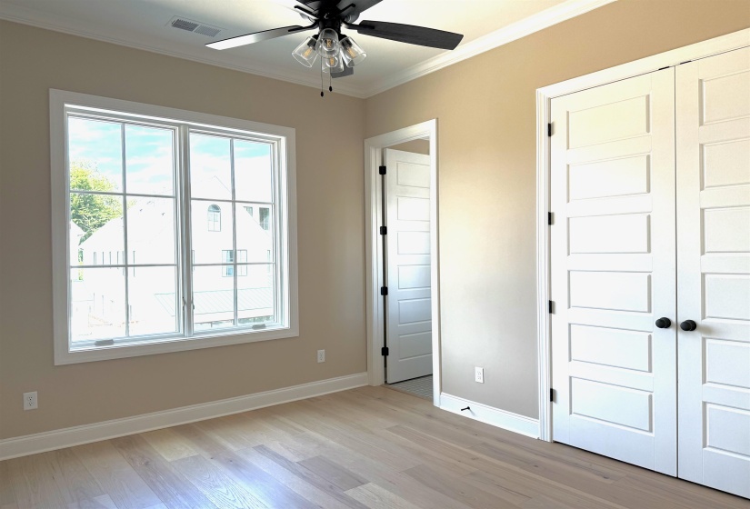 Unfurnished bedroom featuring crown molding, light wood-type flooring, ceiling fan, and a closet