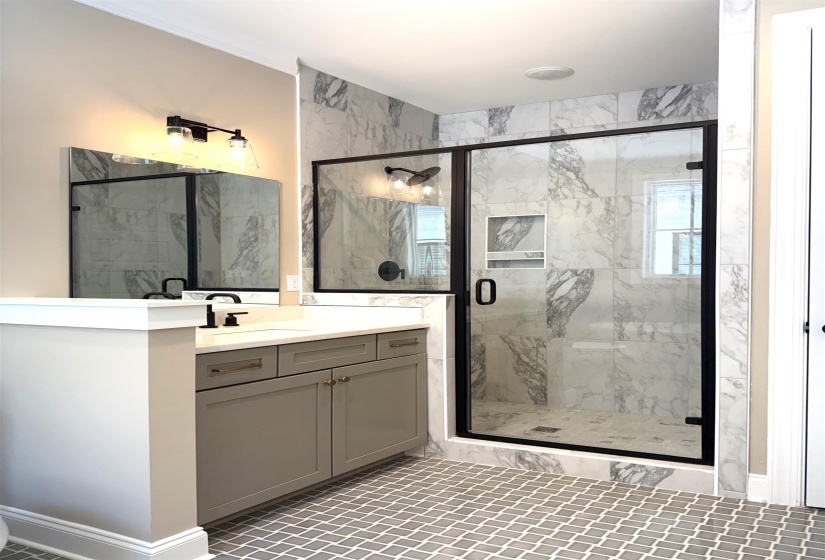 Full bathroom featuring a marble finish shower, vanity, and light tile patterned floors